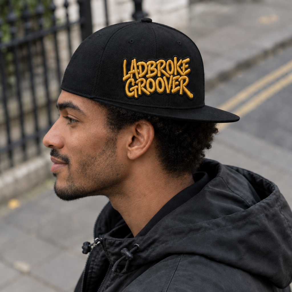Smiling man in profile wearing gold-logo cap